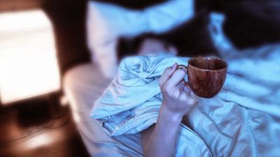 Woman in bed holding coffee cup